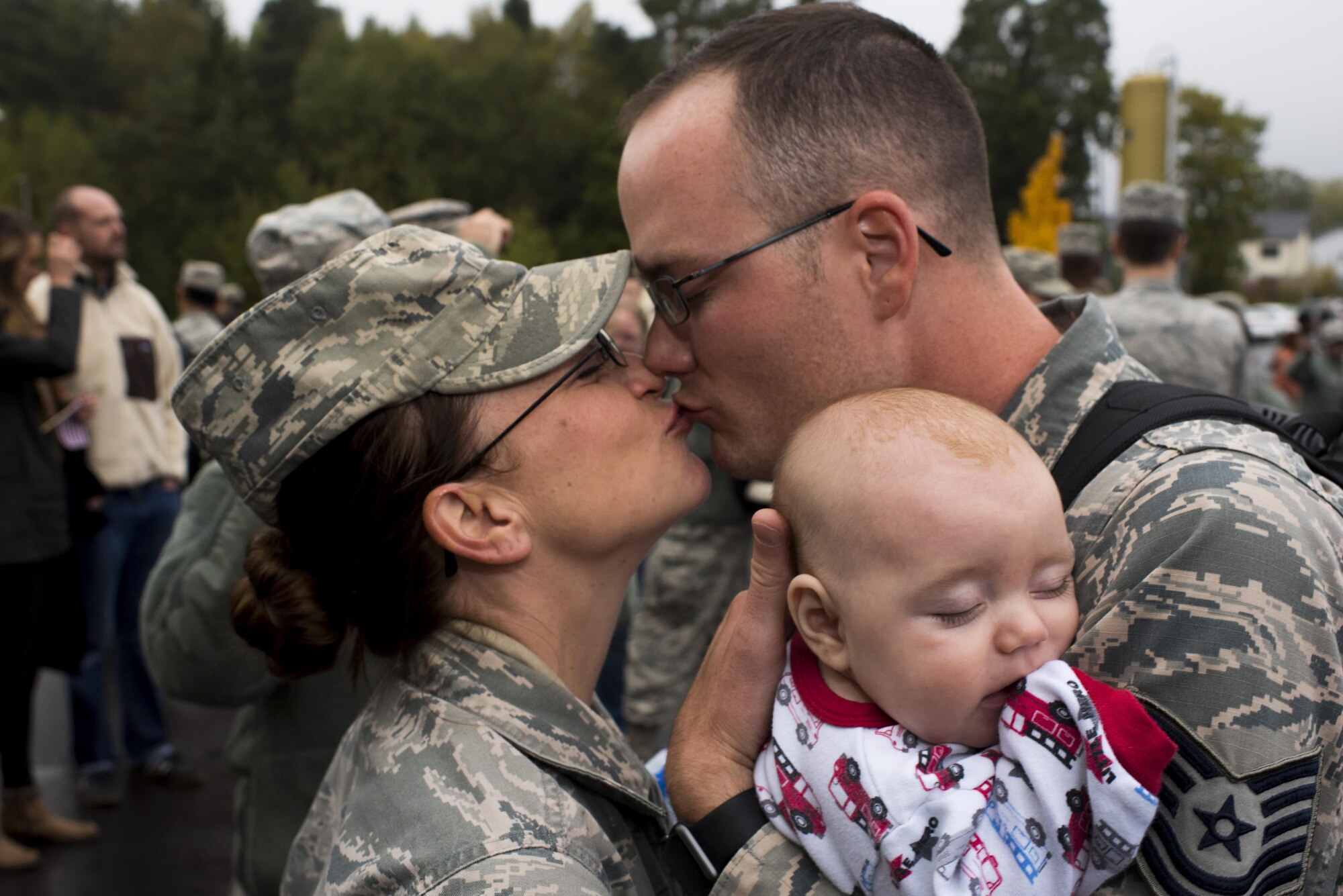 Two Airmen assigned to the 606th Air Control Squadron kiss while holding their infant son, born during the father's deployment, upon the 606th ACS' return to their squadron at Spangdahlem Air Base, Germany, Oct. 20, 2016. Nearly 200 Airmen assigned to the 606th ACS returned, from a six-month rotational deployment to Southwest Asia in support of Operations Freedom’s Sentinel and Inherent Resolve. (U.S. Air Force photo by Staff Sgt. Joe W. McFadden)