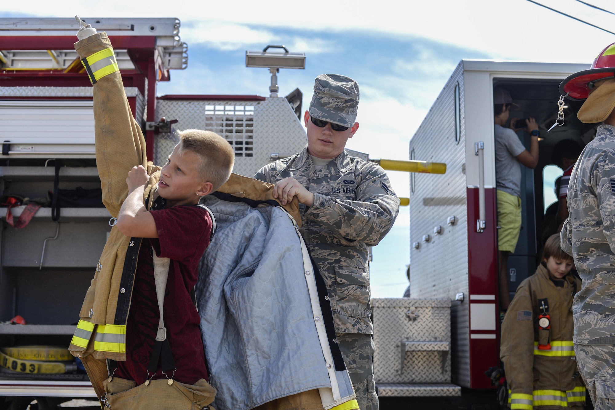A firefighter with the 49th Civil Engineer Squadron Fire Protection Flight helps a student at Holloman Air Force Base’s middle school put on a flame retardant suit as part of the base’s annual Fire Prevention Week, Oct. 13, 2016 at Holloman AFB, N.M. Holloman firefighters taught students about fire safety and prevention, and showcased firefighting equipment to them. (U.S. Air Force photo by Airman 1st Class Alexis P. Docherty)