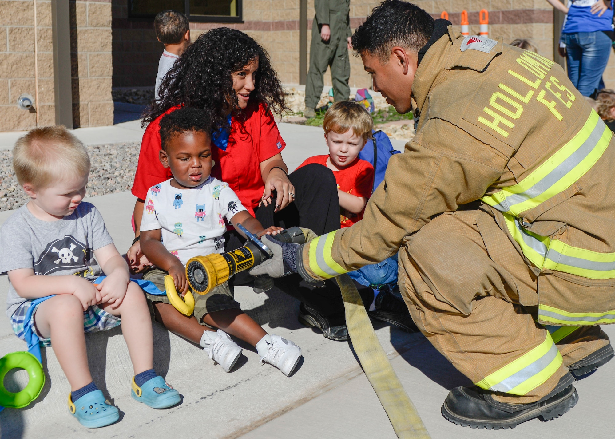 A firefighter with the 49th Civil Engineer Squadron Fire Protection Flight shows three children a fire hose during a visit at the child development center as part of Holloman Air Force Base’s annual Fire Prevention Week, Oct. 14, 2016. Sparky the Fire Dog and members of the 49th Civil Engineer Squadron Fire Protection Flight visited the center to spread awareness about fire safety. (U.S. Air Force photo by Airman 1st Class Alexis P. Docherty)