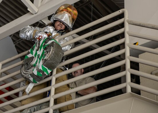 A competitor yanks a high rise pack overtop a stairwell railing during a firefighter muster challenge, as part of Holloman Air Force Base’s annual Fire Prevention Week, Oct. 14, 2016 at Holloman AFB, N.M. The firefighter muster challenge is designed to simulate the various physical stressors that firefighters encounter on a daily basis. Competitors were fitted in flame retardant suits and raced against the clock to complete a variety of tasks, including dummy drags and hose pulls. (U.S. Air Force photo by Airman 1st Class Alexis P. Docherty)