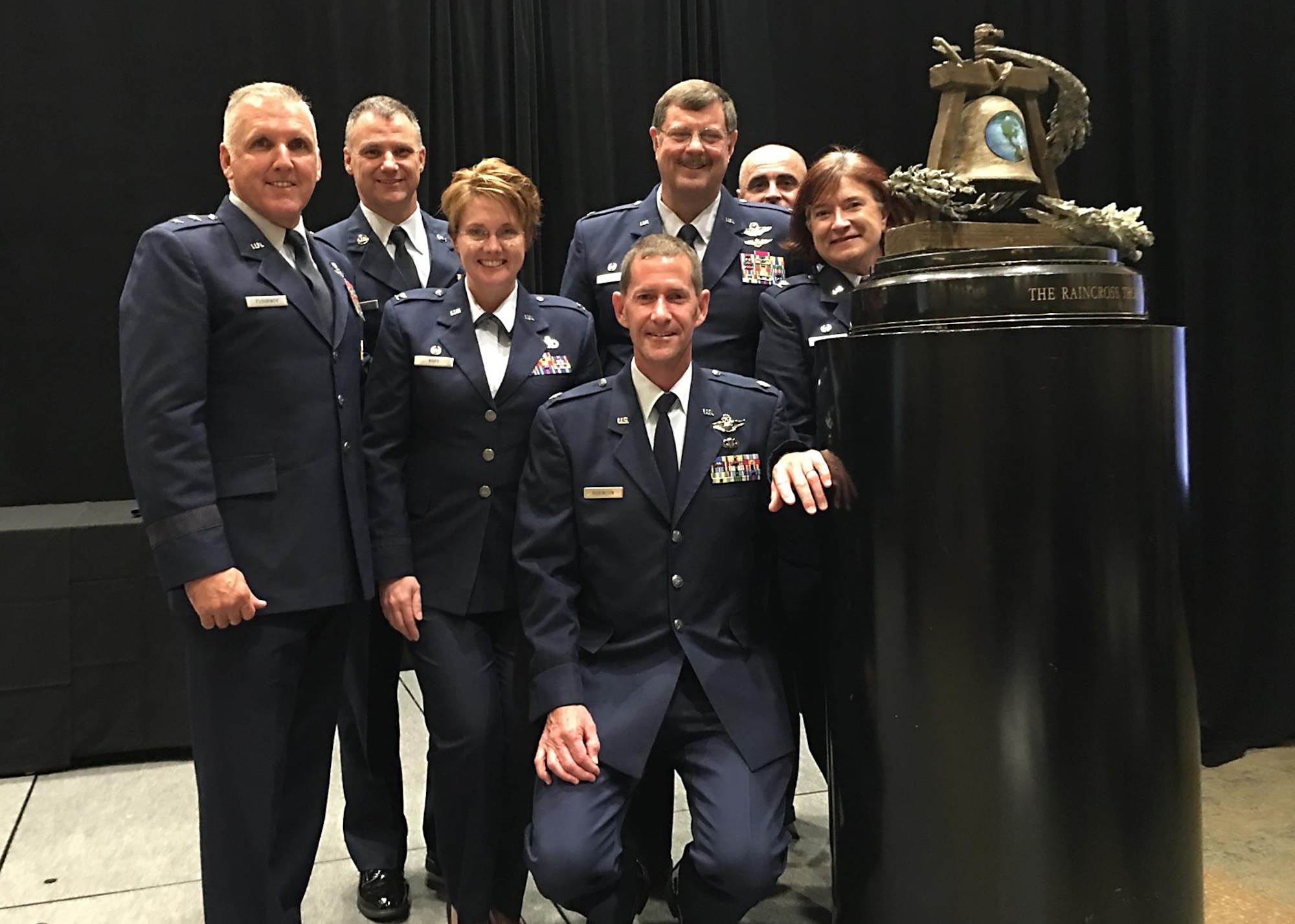 From Left, Maj. Gen. John Flournoy Jr, 4th Air Force commander;  Chief Master Sgt. Mark Barber, 315th Airlift Wing command chief; Col. Cherie Roff, 315th Mission Support Group commander; Lt. Col. John Robinson, 315th Operations Group vice commander (seated); Col. Gregory Gilmour, 315th AW commander; Tech Sgt. Tim Kelly, 315th AW Safety; and Col. Sharon Johnson, incoming 315th Maintenance Group commander, pose with the Raincross Trophy Oct. 20 after the 315th AW received the award at the Raincross Trophy Dinner in Riverside, California. (Courtesy photo)