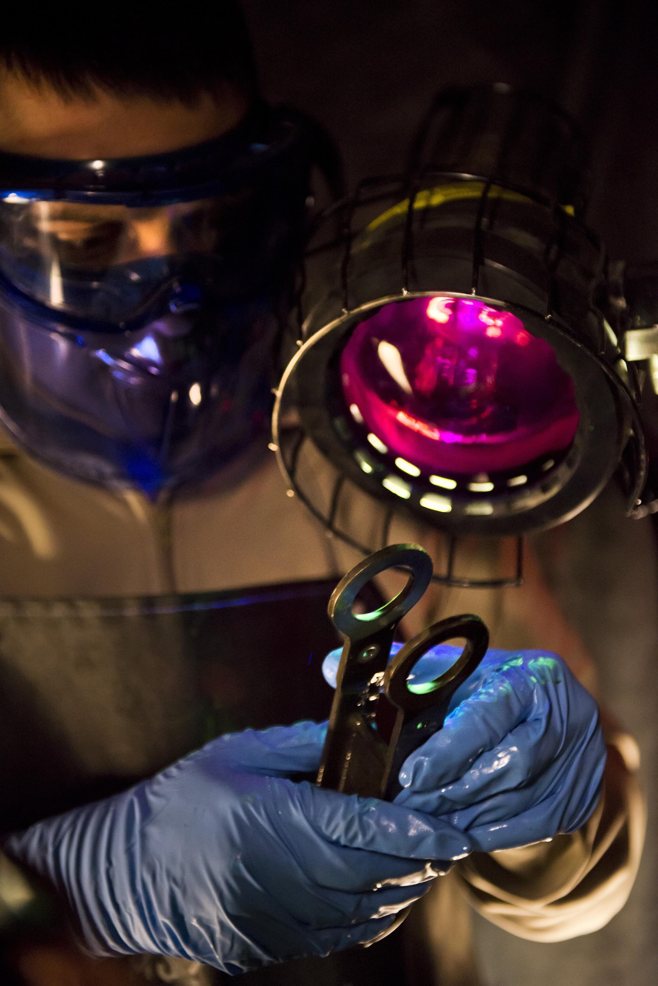 Airman 1st Class Landen Johnston, 5th Maintenance Squadron non-destructive inspection apprentice, performs a magnetic particle inspection under an ultraviolet light at Minot Air Force Base, N.D., Oct. 18, 2016. The fluorescing particles under ultraviolet light allow Airmen to easily locate cracks and imperfections on magnetized aircraft parts. (U.S. Air Force photo/Airman 1st Class J.T. Armstrong)