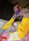 Airman 1st Class Alexander Shaikh, 5th Maintenance Squadron non-destructive inspection journeyman, bathes an aircraft part in an emulsifier at Minot Air Force Base, N.D., Oct. 18, 2016. The emulsifier projects previously applied penetrant in cracks during a fluorescent penetrant inspection. (U.S. Air Force photo/Airman 1st Class J.T. Armstrong)