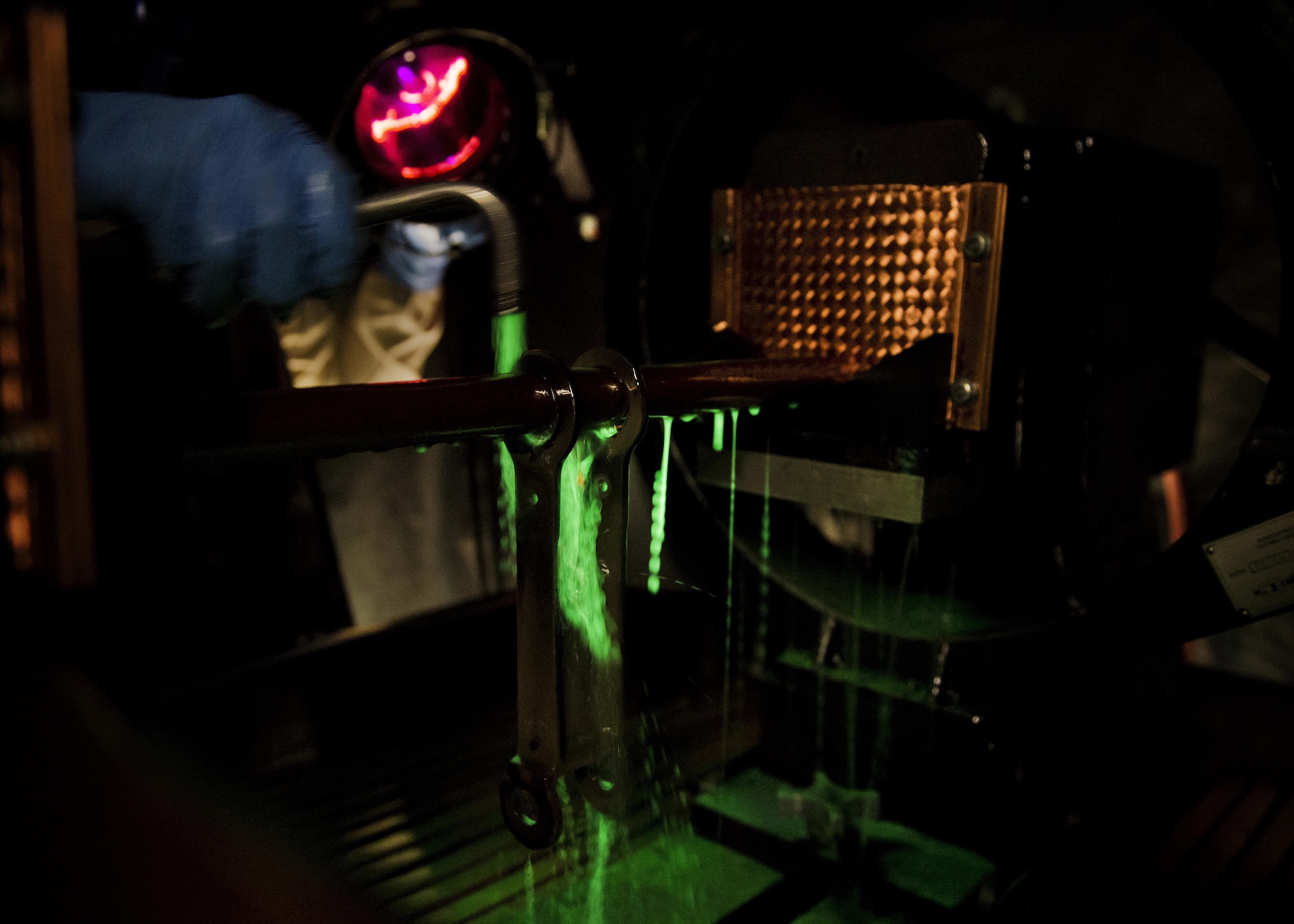 Airman 1st Class Landen Johnston, 5th Maintenance Squadron non-destructive inspection apprentice, coats a magnetized aircraft piece under an ultraviolet light at Minot Air Force Base, N.D., Oct. 18, 2016. The fluorescing particles under ultraviolet light allow Airmen to easily locate cracks and imperfections on magnetized aircraft parts. (U.S. Air Force photo/Airman 1st Class J.T. Armstrong)