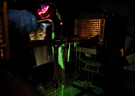 Airman 1st Class Landen Johnston, 5th Maintenance Squadron non-destructive inspection apprentice, coats a magnetized aircraft piece under an ultraviolet light at Minot Air Force Base, N.D., Oct. 18, 2016. The fluorescing particles under ultraviolet light allow Airmen to easily locate cracks and imperfections on magnetized aircraft parts. (U.S. Air Force photo/Airman 1st Class J.T. Armstrong)