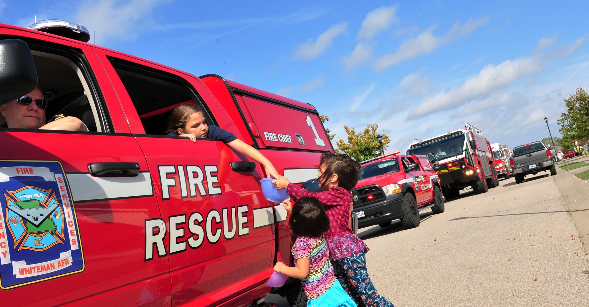 Whiteman leadership pass out candy to base housing residents during a Fire Prevention parade at Whiteman Air Force Base, Mo., Oct. 15, 2016. The fire prevention parade was the finale to Whiteman’s annual fire prevention week.  (U.S. Air Force photo by Senior Airman Jovan Banks)