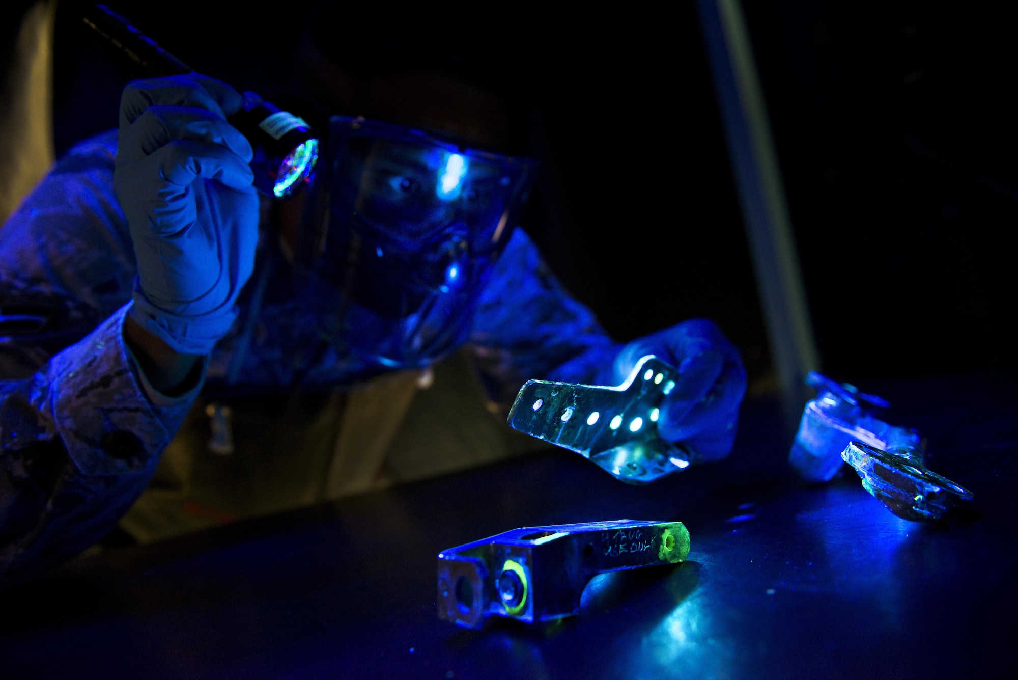 Airman 1st Class Alexander Shaikh, 5th Maintenance Squadron non-destructive inspection journeyman, shines a black light during a fluorescent penetrant inspection at Minot Air Force Base, N.D., Oct. 18, 2016. The black light aids Shaikh in locating cracks and imperfections on parts of the B-52H Stratofortress and aircraft support equipment. (U.S. Air Force photo/Airman 1st Class J.T. Armstrong)