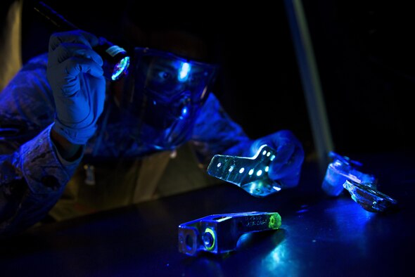 Airman 1st Class Alexander Shaikh, 5th Maintenance Squadron non-destructive inspection journeyman, shines a black light during a fluorescent penetrant inspection at Minot Air Force Base, N.D., Oct. 18, 2016. The black light aids Shaikh in locating cracks and imperfections on parts of the B-52H Stratofortress and aircraft support equipment. (U.S. Air Force photo/Airman 1st Class J.T. Armstrong)