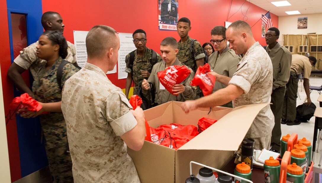 Master Sgt. James Grant (left), G-4, 4th Marine Division, and Master Gunnery Sgt. Neal Stillman (right), G-3 chief, 4th Marine Logistics Group, pass out gift bags to cadets in support of Red Ribbon Week at New Orleans Military and Maritime Academy, Oct. 20, 2016. Every year in October, NOMMA invites Marines from Marine Forces Reserve to speak with cadets about the dangers of drug and alcohol addiction. (U.S. Marine Corps photo by Lance Cpl. Dallas Johnson/Released) 