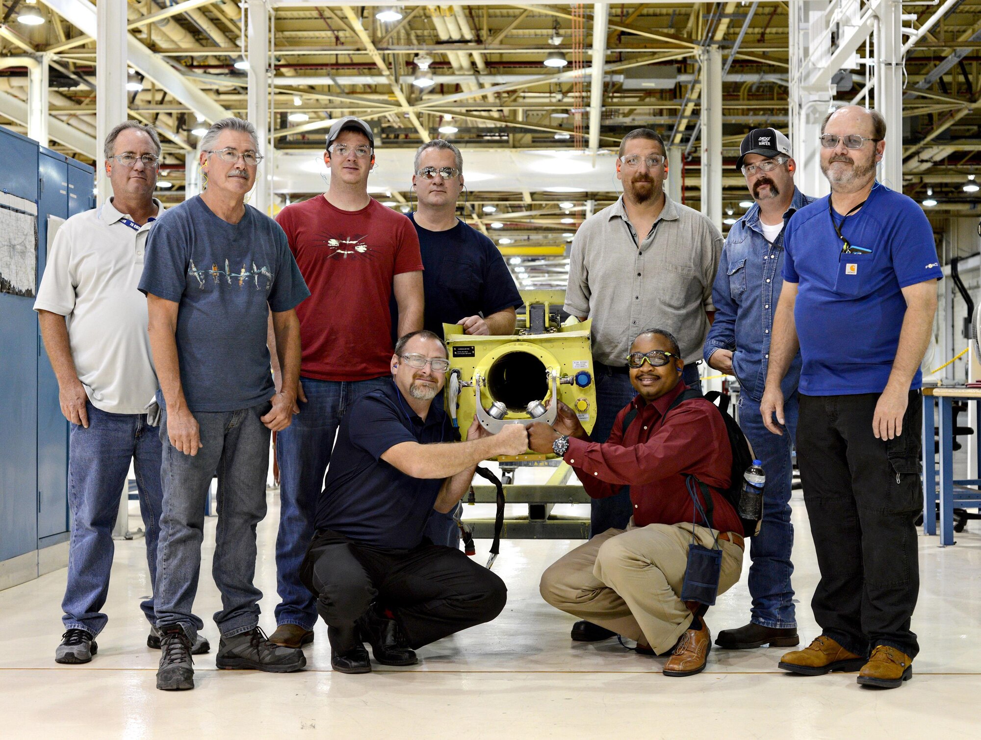 Members of the 76th Commodities Maintenance Group’s boom shop and representatives from the Voluntary Protection Programs Integrated Design Team (VPP IDT) show off their design of a boom tube roller (working/non-official name), which they planned and executed together out of used existing parts. The $50 fix will help workers with the difficult and labor-intensive task of inserting the boom into the boom housing and not cause physical pain. Standing, from left, are Roy Arnold, 550th Commodities Maintenance Squadron; Joe Harder, 551st CMXS; Ryan Adkins, 550th CMXS; Travis Saylor, 551st CMXS; Marvin Walker, 550th CMXS; Ryan Kilgore, 550th CMXS; and Roger Holder, 550th CMXS. Kneeling are Richard Meese and Joseph Milton with the Integrated Design Team Voluntary Protection Program. (Air Force photo by Kelly White)