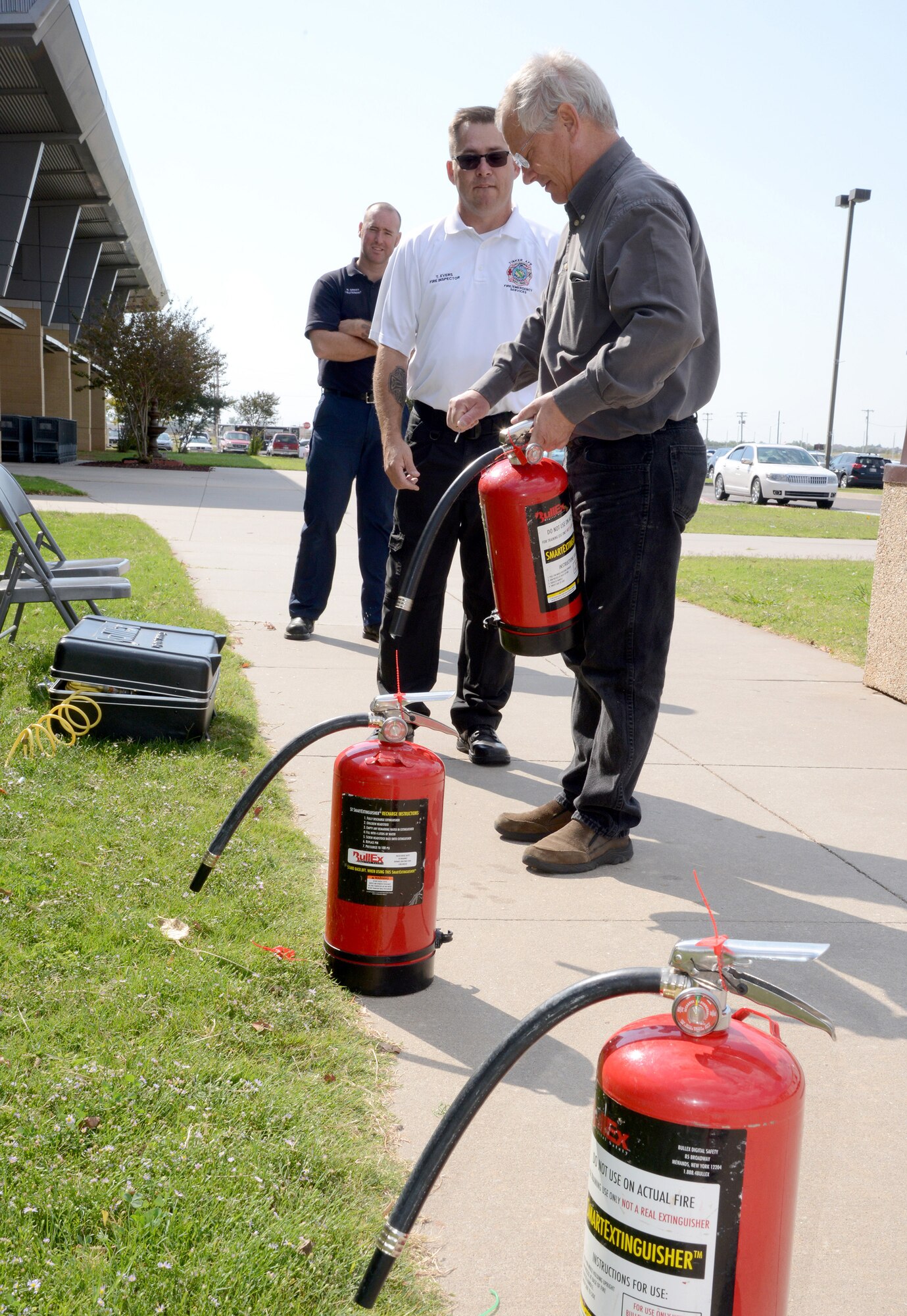 Bill Green and Todd Evers showed Dan Henry, with AAFES, how to properly use a fire extinguisher. Employees of the Base Exchange are required to have commercial cooking and fire extinguisher training twice a year. (Air Force photo by Kelly White)