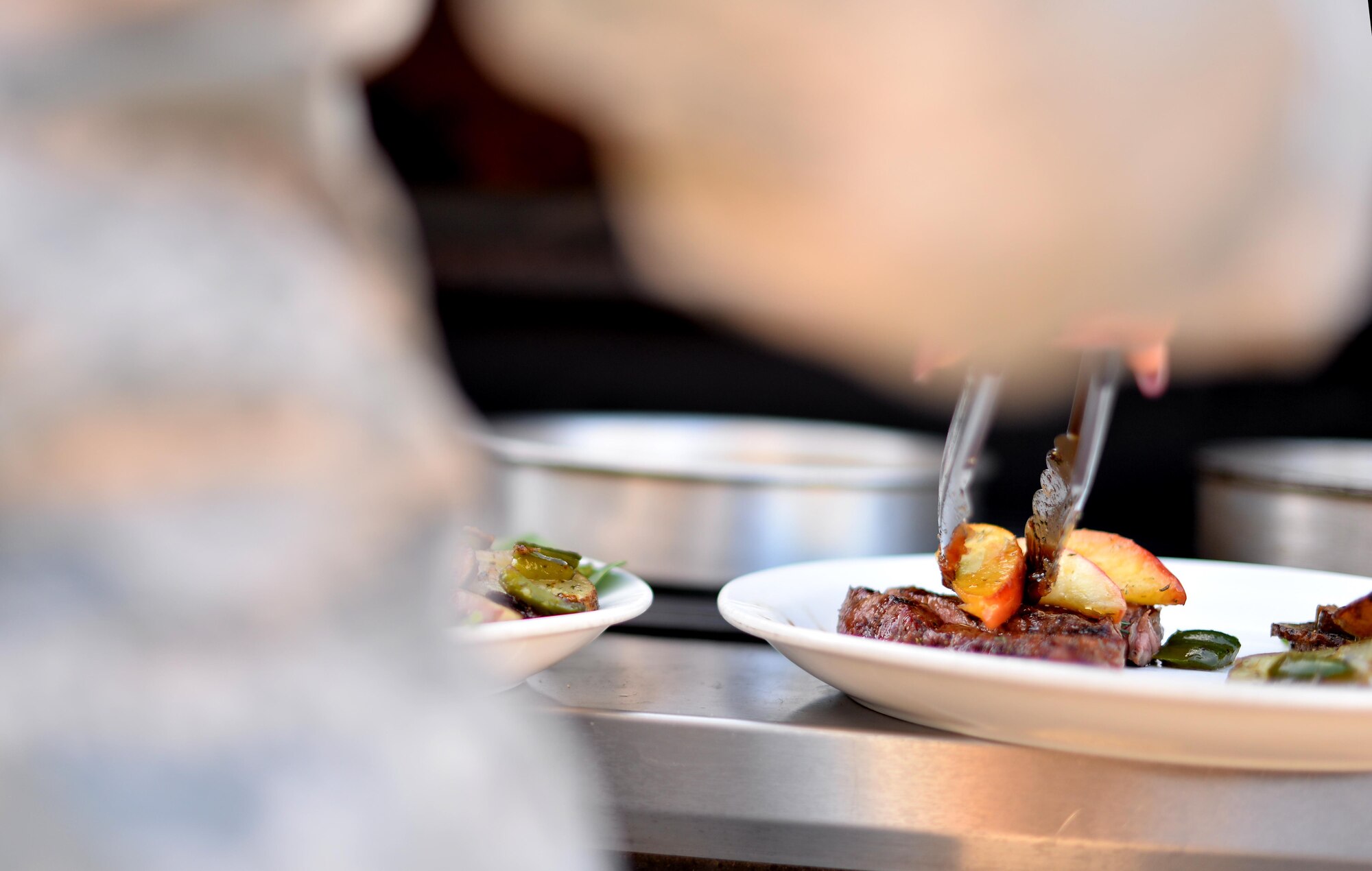 U.S. Air Force Senior Airman Ashanta Williams, 55th Force Support Squadron food service specialist, garnishes a medium-well steak with sautéed herbed brown sugar apples while competing in the Iron Chef Grill Masters competition at the Ronald L. King Dining Facility Oct 13, Offutt Air Force Base, Neb.  This is the second Iron Chef competition in where force support Airmen had a chance to showcase their culinary talents.  (U.S. Air Force photo by Josh Plueger)