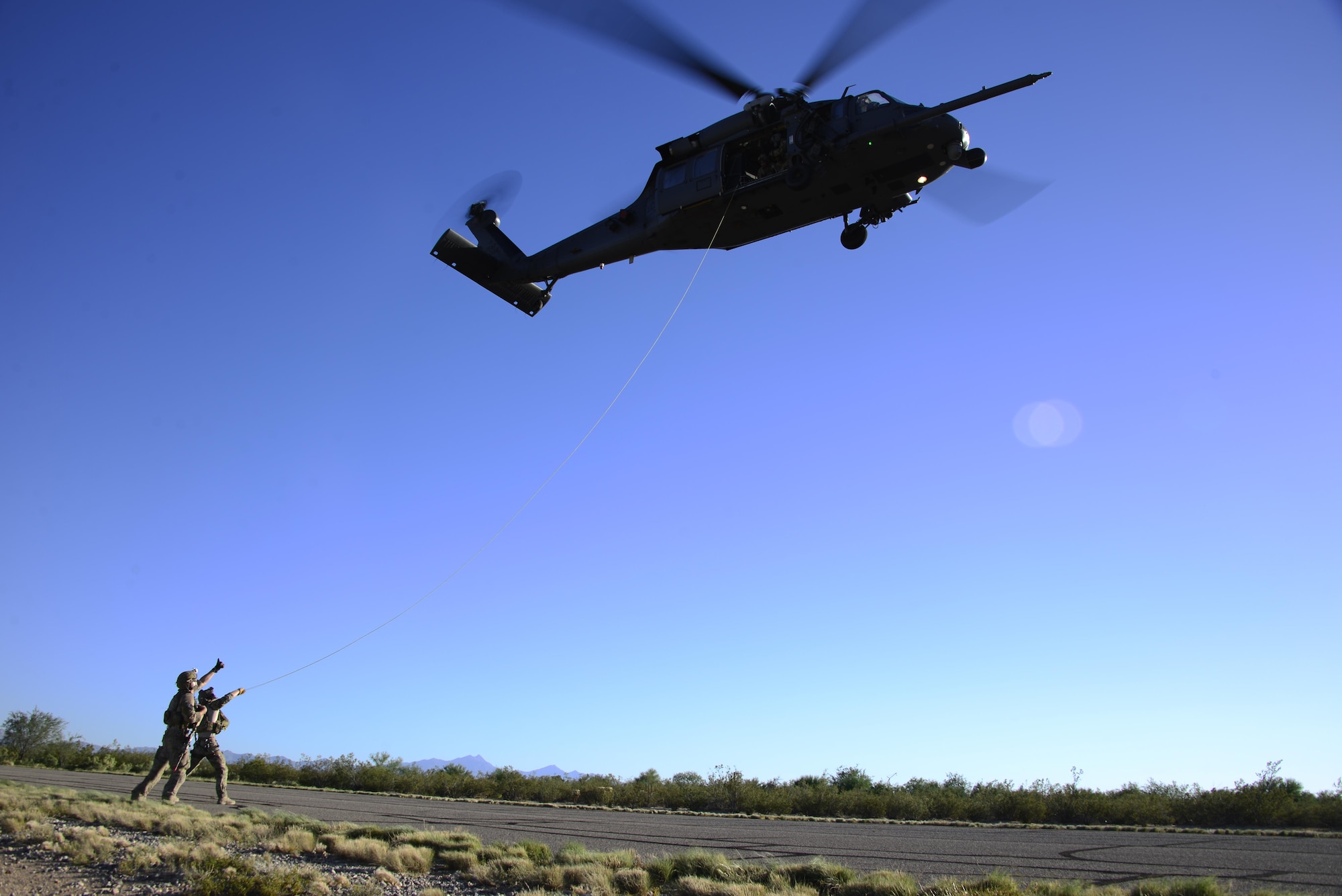 Pararescuemen assigned to the 48th Rescue Squadron signal to an Airman in an HH-60G Pave Hawk during alternate insertion/extraction training at Davis-Monthan Air Force Base, Ariz., Oct. 18, 2016. The Airmen are required to perform AIE training every year and do multiple iterations throughout the year to maintain proficiency in all the methods. (U.S. Air Force photo by Senior Airman Betty R. Chevalier)