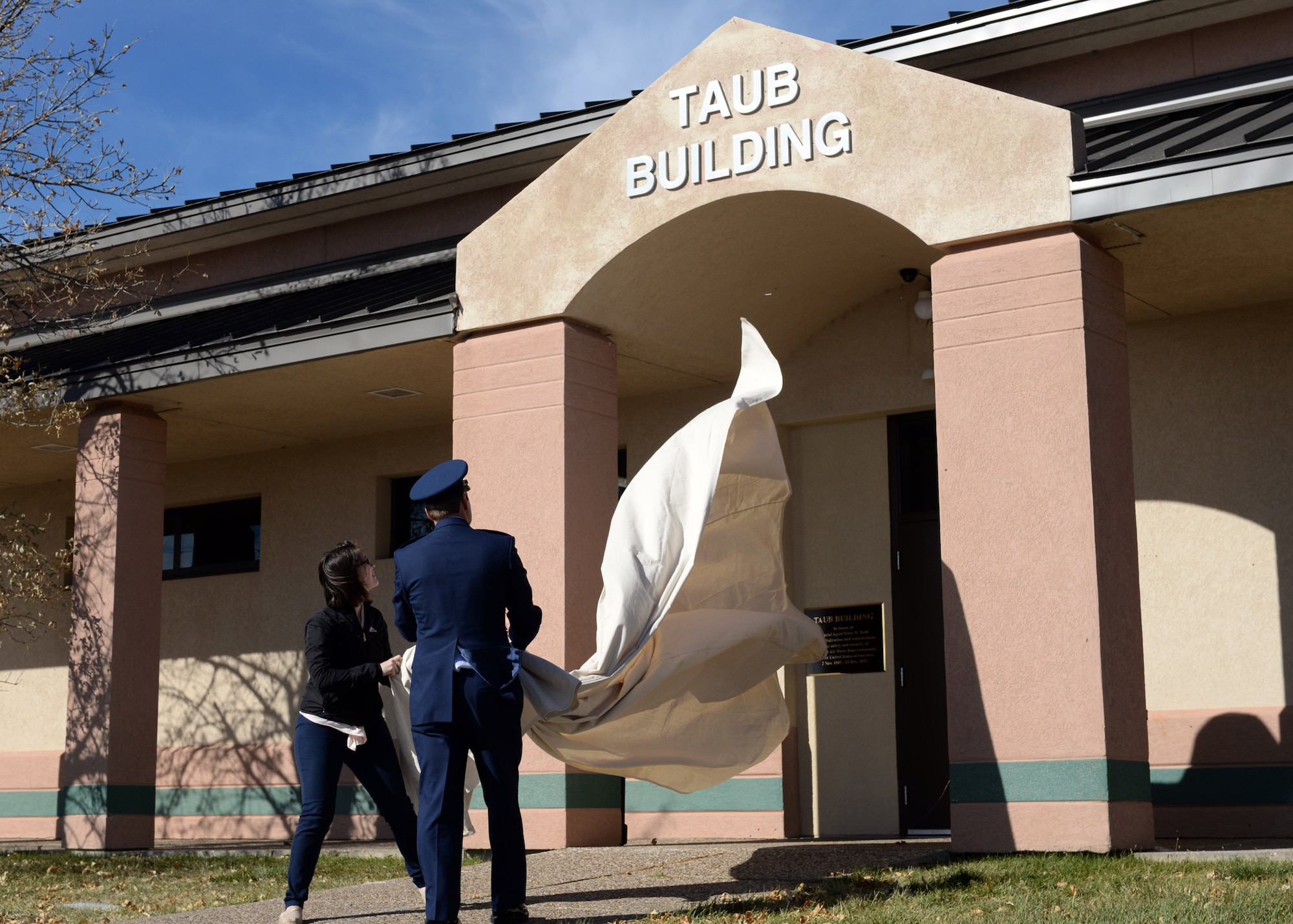 Christina Taub, the wife of the late Special Agent Peter Taub, and SA Christopher Joers, commander of Air Force Office of Special Investigations Detachment 816, unveil the new name of the OSI building during a dedication ceremony at Ellsworth Air Force Base, S.D., Oct. 21, 2016. In addition to the building dedication, a monument was also placed in Ellsworth’s Memorial Park in honor of SA Taub. (U.S. Air Force photo by Airman 1st Class Denise M. Jenson)