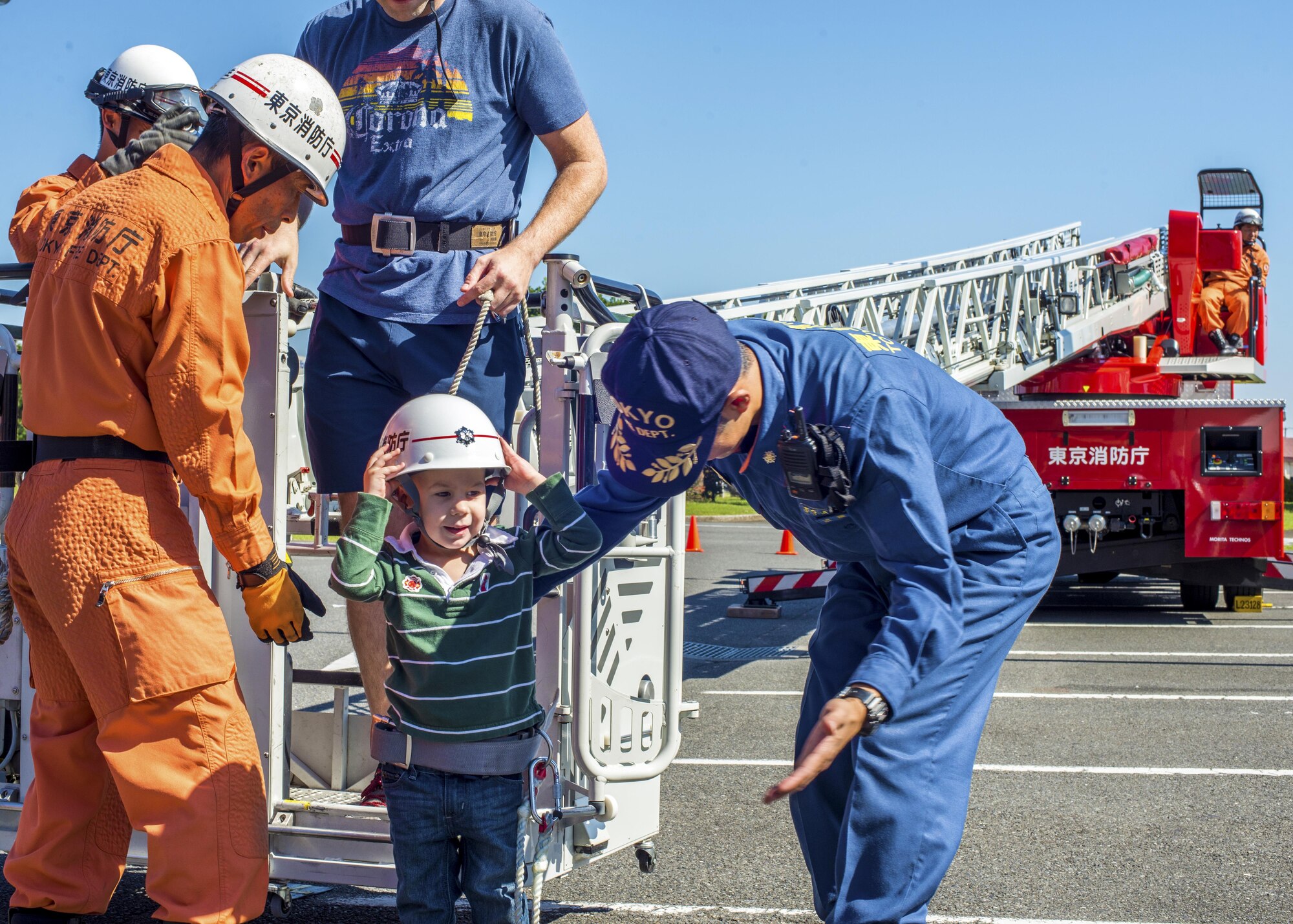 A child is escorted off an extending fire truck ladder at the Yokota Community Center during Fire Prevention Week on 15 Oct. 2016 at Yokota Air Base, Japan. The event included static displays of various firefighting equipment used by 374th Civil Engineer Squadron firefighters, Japan Air Self-Defense Force Fire and Rescue and the Tokyo Fire Department. (U.S. Air Force Photo by Airman 1st Class Donald Hudson/Released)