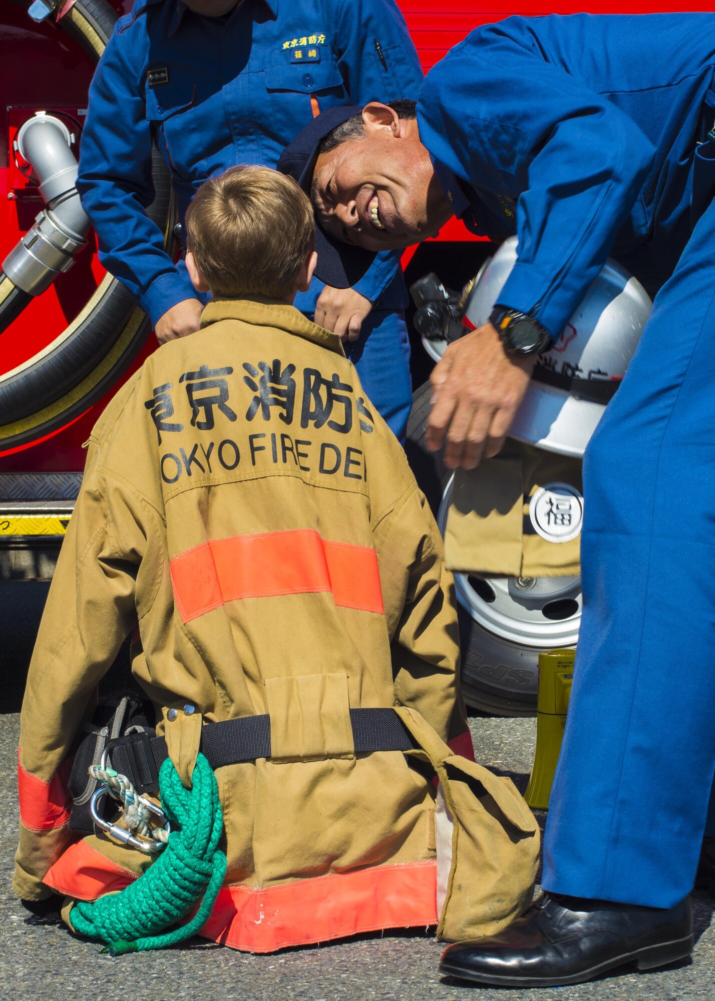 Firefighters from the Tokyo Fire Department help a child try on firefighting protective equipment at the Yokota Community Center during Fire Prevention Week on 15 Oct. 2016 at Yokota Air Base, Japan. The event included static displays of various firefighting equipment used by 374th Civil Engineer Squadron firefighters, Japan Air Self-Defense Force Fire and Rescue and the Tokyo Fire Department. (U.S. Air Force Photo by Airman 1st Class Donald Hudson/Released)
