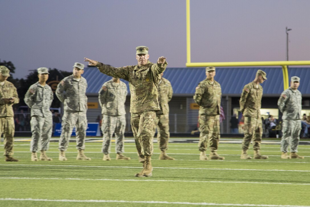 1st Sgt. Brian Jarvis, 316th Sustainment Command (Expeditionary) Headquarters and Headquarters Company 1st Sgt., directs Army Reserve Soldiers on to the Gatesville High School football field before a game in Gatesville, Tx., Oct. 21, 2016. (U.S. Army photo by Staff Sgt. Dalton Smith)