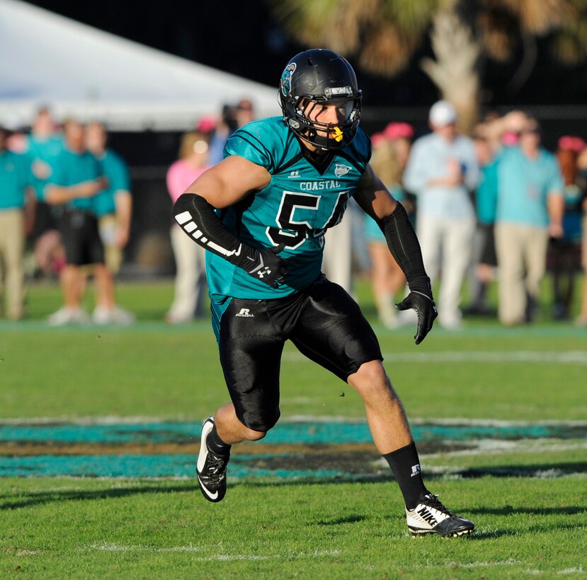 Second Lieutenant Tyler R. Watkins defends his zone as Coastal Carolina University’s linebacker during the final game of the regular season, facing off against Charleston Southern University at Brooks Stadium, Conway, S.C., Oct. 25, 2014. Watkins applied everything he learned playing football to his training at Officer Candidates School aboard Marine Corps Base Quantico, Va. He graduated OCS with Officer Candidate Class 222, which had the most OCS graduates since 2009, on Aug. 6, 2016. Due to injuries sustained during OCS, he is temporarily assigned to the Plans and Research section at Marine Corps Recruiting Command aboard MCB Quantico. Watkins hopes to return to training in March 2017.