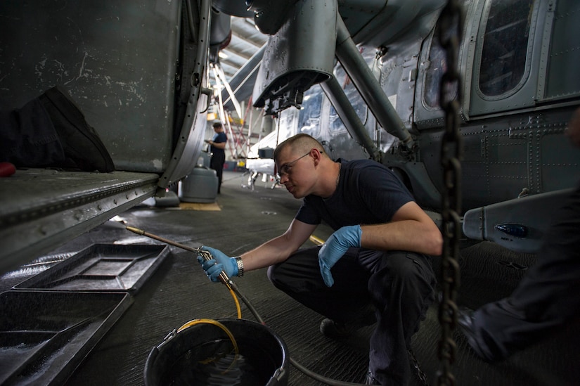 Navy Petty Officer 1st Class James Grider uses an atomizer to blast off sand and dirt of a MH-60S Sea Hawk helicopter assigned to the Dusty Dogs of Helicopter Sea Combat Squadron 7 in the hangar bay of the aircraft carrier USS Dwight D. Eisenhower. The Eisenhower Carrier Strike Group is deployed in support of Operation Inherent Resolve, maritime security operations and theater security cooperation efforts in the U.S. 5th Fleet area of operations. Navy photo by Petty Officer 3rd Class Andrew J. Sneeringer