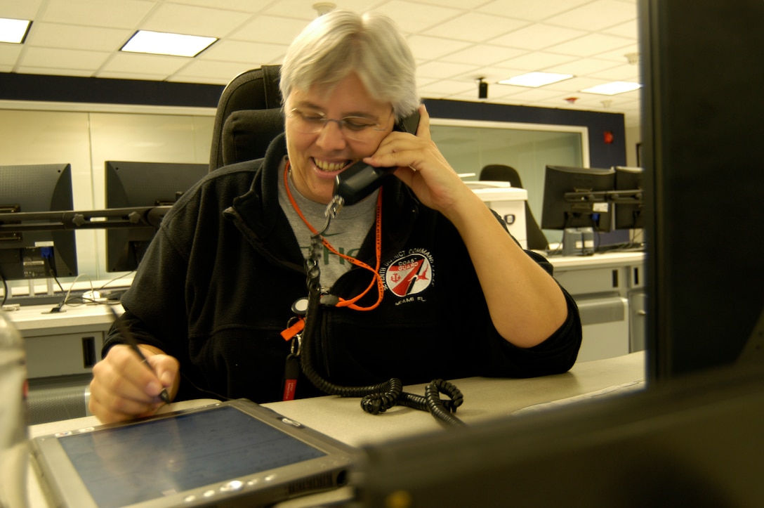 A Coast Guard civilian employee stands watch as the command duty officer in the
Seventh District Command Center.  The CDO is the senior person on watch in the district's command center and is responsible for overseeing the execution of search and rescue operations, law enforcement activities and integration of intelligence information during their 12-hour watches. Unlike their military counterparts who rotate assignments every three to four years, Coast Guard civilian employees remain at the command center, providing continuity and a wealth of experience and local knowledge. (U.S. Coast Guard Photo by Lt. Cmdr. C. T. O'Neil)                                