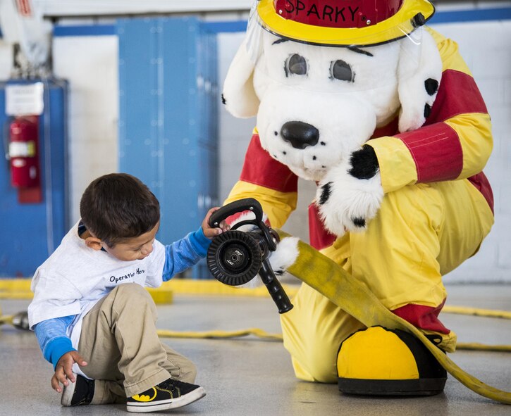 Sparky the Fire Dog explains how to use a fire hose to a new recruit during the Operation Hero event Oct. 22 at Eglin Air Force Base, Fla.  More than 100 kids participated in the mock deployment experience created to give military children a glimpse of what their loved ones go through when they leave home. The kids went through a deployment line to get their dog tags and “immunizations” before they were briefed by the commander and shipped off to a deployed location. There, they participated in various activities and demonstrations by local base agencies. (U.S. Air Force photo/Samuel King Jr.)