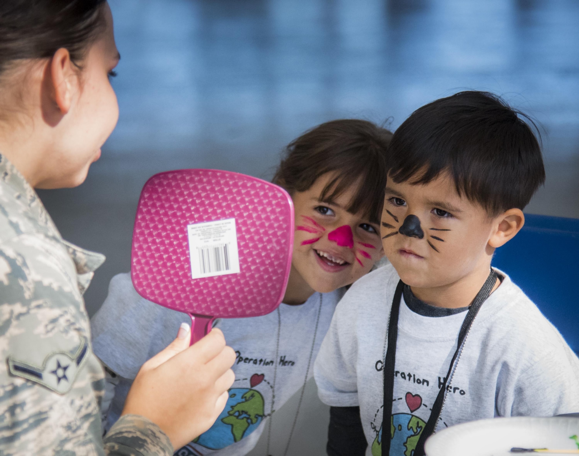 A brother and sister admire their new cat face paint during the Operation Hero event Oct. 22 at Eglin Air Force Base, Fla.  More than 100 kids participated in the mock deployment experience created to give military children a glimpse of what their loved ones go through when they leave home. The kids went through a deployment line to get their dog tags and “immunizations” before they were briefed by the commander and shipped off to a deployed location. There, they participated in various activities and demonstrations by local base agencies. (U.S. Air Force photo/Samuel King Jr.)