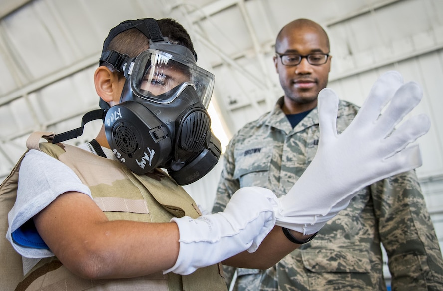 A new recruit tries on his protective chemical gear during the Operation Hero event Oct. 22 at Eglin Air Force Base, Fla.  More than 100 kids participated in the mock deployment experience created to give military children a glimpse of what their loved ones go through when they leave home. The kids went through a deployment line to get their dog tags and “immunizations” before they were briefed by the commander and shipped off to a deployed location. There, they participated in various activities and demonstrations by local base agencies. (U.S. Air Force photo/Samuel King Jr.)