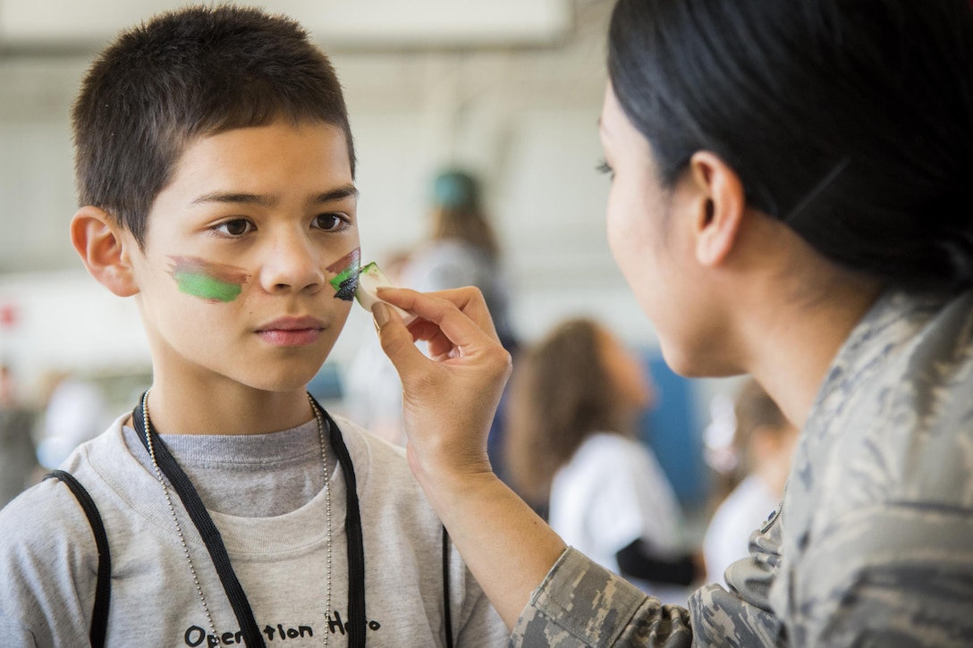 An airman paints a child's face during an Operation Hero event at Eglin Air Force Base, Fla., Oct 22, 2016. The event teaches military children about the process their parents go through when they leave home for deployments. Air Force photo by Samuel King Jr.