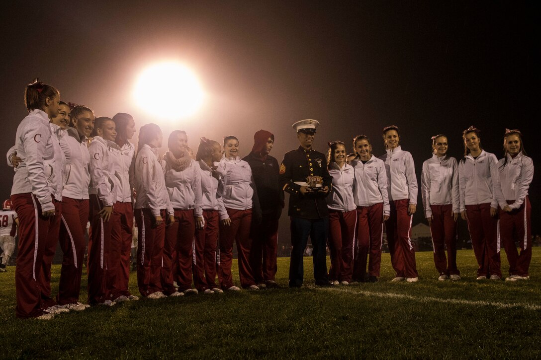 Sergeant Rojjee Pangilinan, a canvassing recruiter with Recruiting Substation Central Maine, stands with cheerleaders of Cony High School in Cony, Maine, during their football game against Gardiner High School in Gardiner, Maine, Oct. 21. The game is part of the Great American Rivalry Series, a series of high school football games between schools with historic sports rivalries. During and after the game, the Marines and GARS recognized football players with the highest GPA of their teams and players that contributed most to the game and the sport as a whole.