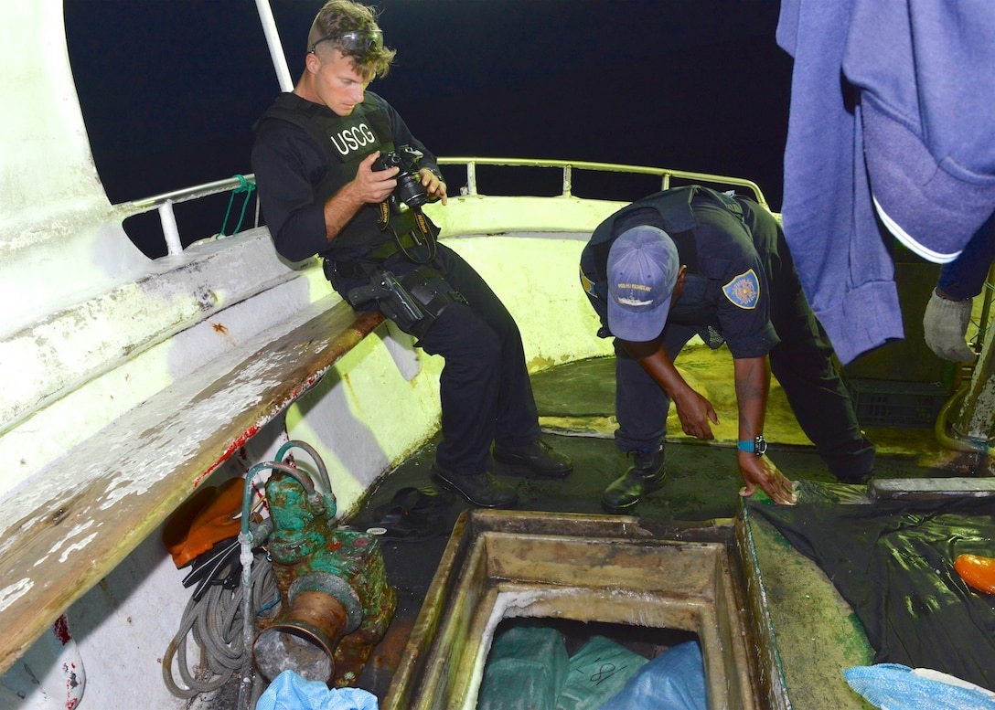 U.S. Coast Guard Petty Officer 1st Class Brett Malone, a damage controlman and boarding team member, with Jim Kloulechad, a Palau National Police officer, photographs the catch of the longline fishing vessel Shin Jinn Lih during a fisheries boarding in the Palau exclusive economic zone Sept. 5, 2016. The boardings were conducted under a U.S. Coast Guard and Palau bilateral agreement. (U.S. Coast Guard photo by Chief Petty Officer Sara Mooers)