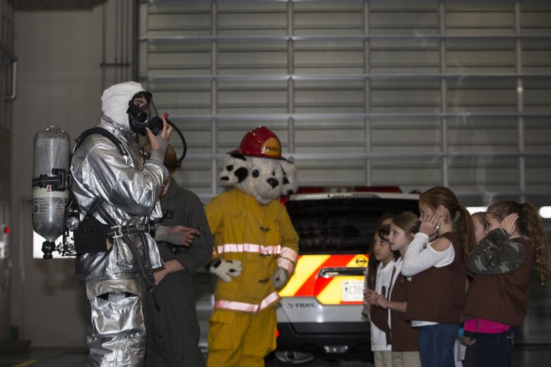 U.S. Marine Corps Lance Cpl. Jacob Johnson, firefighting specialist with Aircraft Rescue and Firefighting, demonstrates how the firefighting gear works for Brownies of the Iwakuni Brownies Troop 92 during a fire prevention and safety seminar on Marine Corps Air Station Iwakuni, Japan, Oct. 22, 2016. As part of the seminar, the Marines demonstrated how quickly they can put their gear on and the importance of fire safety basics. (U.S. Marine Corps photo by Lance Cpl. Joseph Abrego)