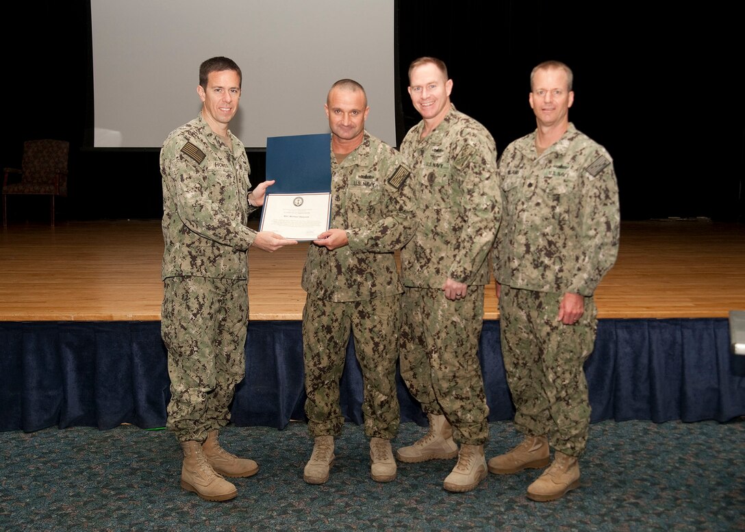 Chief Petty Officer Michael Hancock, center, receives a letter of appreciation for his work and command coordination efforts in the 2016 Navy-Marine Corps Relief Society fundraising drive at the multipurpose room aboard Naval Support Activity Bahrain, Oct. 23, 2016. The Navy-Marine Corps Relief Society is to provide emergency financial assistance to active duty and retired Navy and Marine Corps personnel and their families.