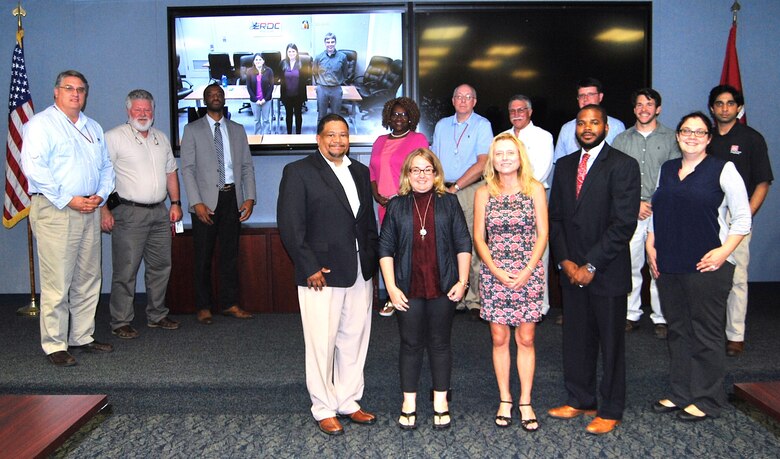 Four teams from across ERDC presented their solutions using the organization's "Innovation Alley" process. Front row from left: Chris Lunderman, Lacey Duckworth, Andrea Scott, Darryl Carson, Jen Seiter. Second row from left: Dr. Gary Anderton, Dr. Reed Mosher, Quincy Alexander, Terri Lewis, Dr. Jeffery Holland, Danny Harrelson, Jared Johnson, Luke Gurtowski, Devin Sham. On screen from left: Julie Parno, Samantha Sinclair and Matthew Parno.