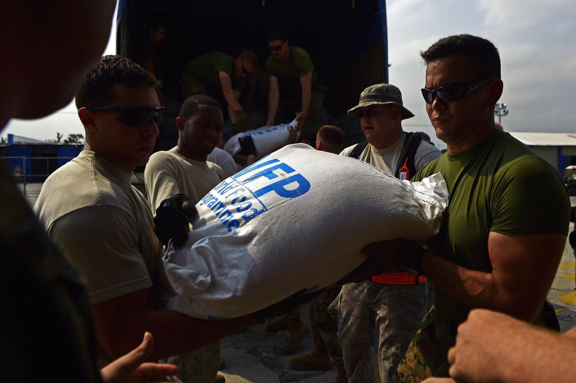 U.S. service members unload rice from a World Food Programme truck onto a CH-47, Oct. 11, 2016 in Port-Au-Prince, Haiti. The Airmen are working alongside Haitian citizens to provide relief after the nation was struck by Hurricane Matthew. (U.S. Air Force Photo by Tech. Sgt. Russ Scalf)