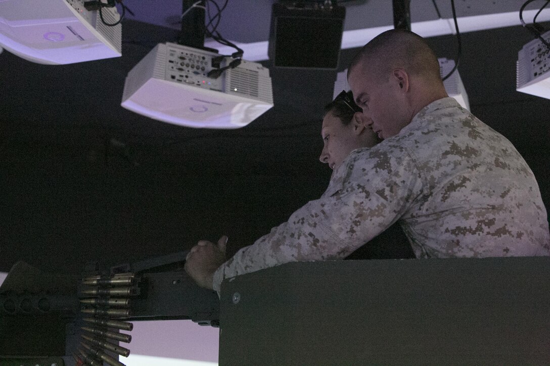Lance Cpl. Brian Powell, team leader, 1st Battalion, 7th Marine Regiment, shows his wife, Stacy, how to utilize an M2 Browning .50 caliber machine gun, in the Combat Convoy Simulator at Camp Wilson aboard Marine Corps Air Ground Combat Center, Twentynine Palm, Calif., Oct. 14, 2016. (Official Marine Corps photo by Cpl. Thomas Mudd/Released)