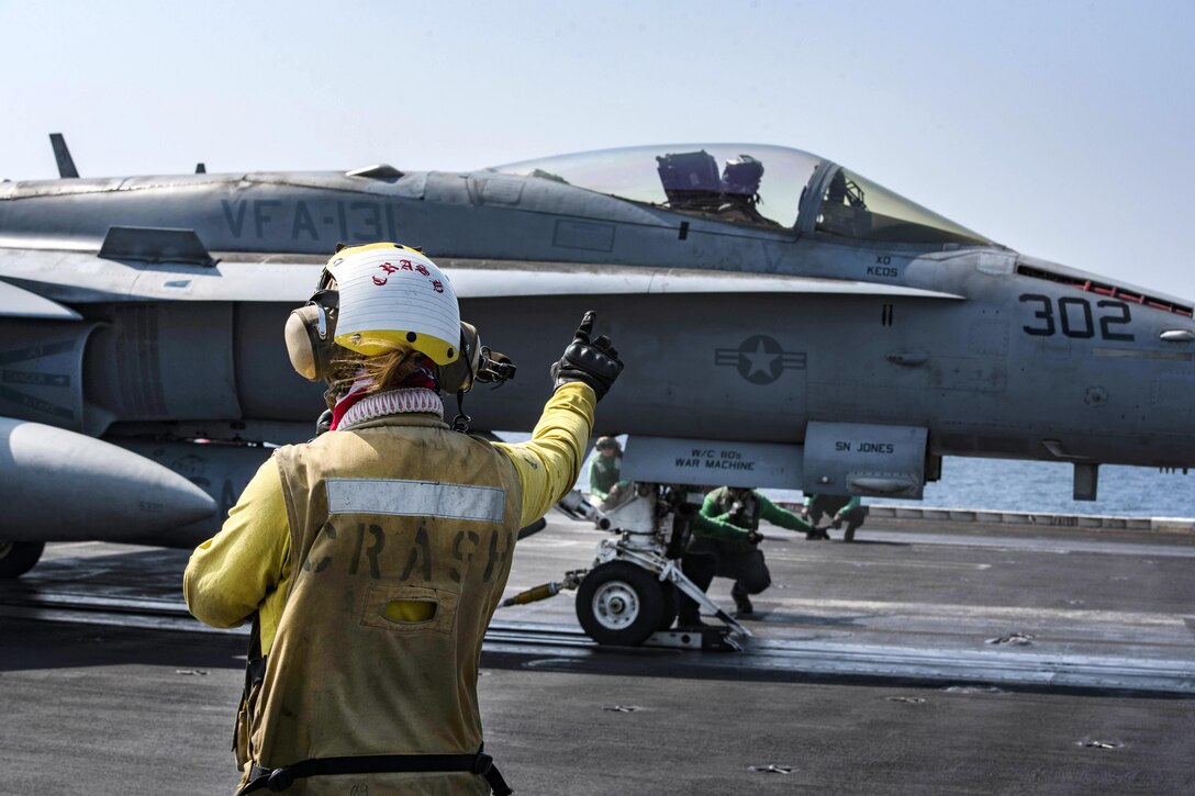 Navy Petty Officer 3rd Class Gabrielle Embry signals to an F/A-18F Super Hornet on the flight deck of the aircraft carrier USS Dwight D. Eisenhower in the Persian Gulf, Oct. 20, 2016. The pilot and aircraft are assigned to Strike Fighter Squadron 131. Embry is an aviation boatswain’s mate. Navy photo by Petty Officer 3rd Class Nathan T. Beard