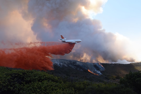 An aircraft helps extinguish a portion of a fire at Vandenberg Air Force Base, California, Sept. 20, 2016.  Apart from the South Base fire, the North Base had fires burning in separate areas, one of which jeopardized the 21st Space Operations Squadron’s Ellison Onizuka Satellite Operations Facility, forcing personnel to evacuate. (U.S. Air Force photo/Staff Sgt. Shane Phipps)