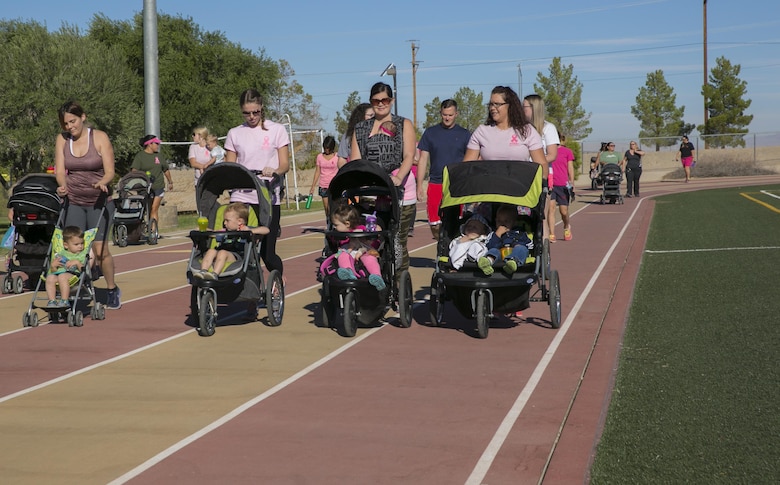 Marine Corps Air Ground Combat Center patrons walk around the track with their children during the Officers' Spouses' Club third annual Pink Breast Cancer Awareness Walk at Felix Field aboard the Marine Corps Air Ground Combat Center, Twentynine Palms, Calif., Oct. 14, 2016. OSC hosted the walk to raise awareness and money for breast cancer research. (Official Marine Corps photo by Lance Cpl. Dave Flores/Released)