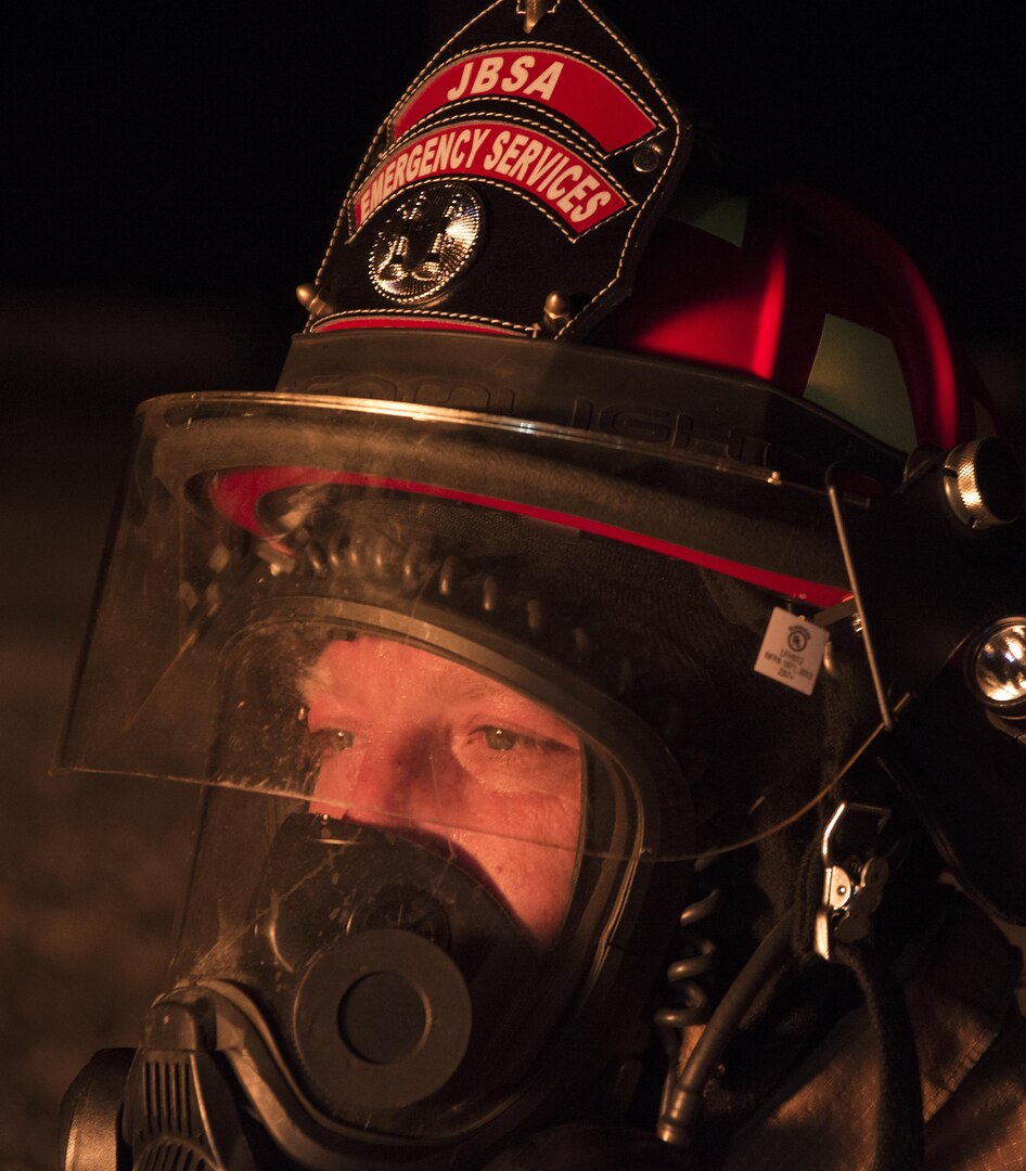 Kenneth Adkins, Joint Base San Antonio-Randolph Fire Emergency Services lead firefighter, watches a team of firefighters extinguish an aircraft engine fire during night fire training at the Camp Talon fire training grounds on JBSA-Randolph Oct. 17, 2016. Live fire training is required on a recurring basis and the JBSA-Randolph Fire Departments aims to conduct the training at least once every six months. 