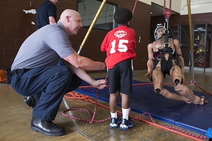 Alan Adams (left), Joint Base San Antonio-Randolph Fire Emergency Services lead firefighter, helps Jeremiah Jones work a pulley to lift a dummy during the JBSA Fire Prevention Week open house at JBSA-Randolph Oct. 15, 2016. JBSA FES is following the Fire Prevention Week theme “Don’t Wait – Check the Date! Replace Smoke Alarms Every 10 Years” in stressing to JBSA residents and the public the importance of properly functioning smoke alarms and smoke alarm safety. 