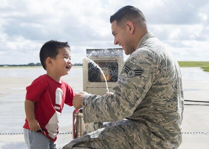 Senior Airman Christopher Flores (right), Joint Base San Antonio-Randolph Fire Emergency Services firefighter, helps Julian Kurtz put out a fire during the JBSA Fire Prevention Week open house at JBSA-Randolph Oct. 15, 2016. During Fire Prevention Week, JBSA Fire Emergency Services fire inspectors encouraged families to go over their escape plans in case of a fire as often as needed until every family member is familiar with it. 