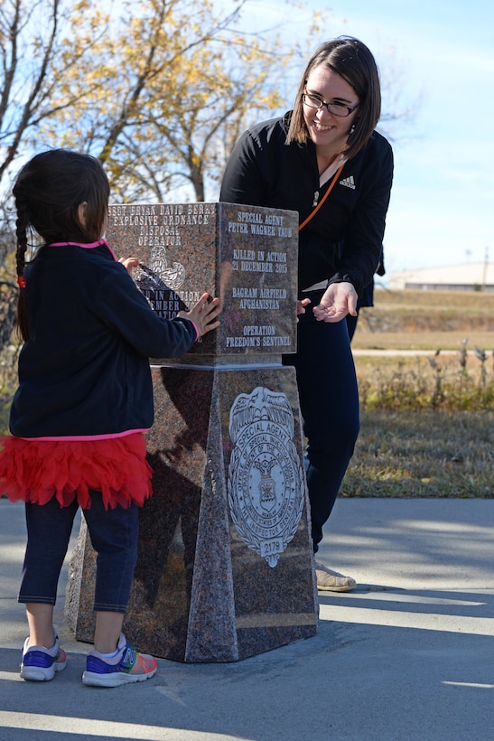 Penelope and Christina Taub, daughter and wife of the late Special Agent Peter Taub, Air Force Office of Special Investigations agent, look at a memorial during an unveiling ceremony at Ellsworth Air Force Base, S.D., Oct. 21, 2016. The memorial was donated by the Rapid City Chamber of Commerce to honor the memory of Taub, who was killed in action near Bagram Airfield, Afghanistan, Dec. 21, 2015. (U.S. Air Force photo by Senior Airman Rebecca Imwalle) 
