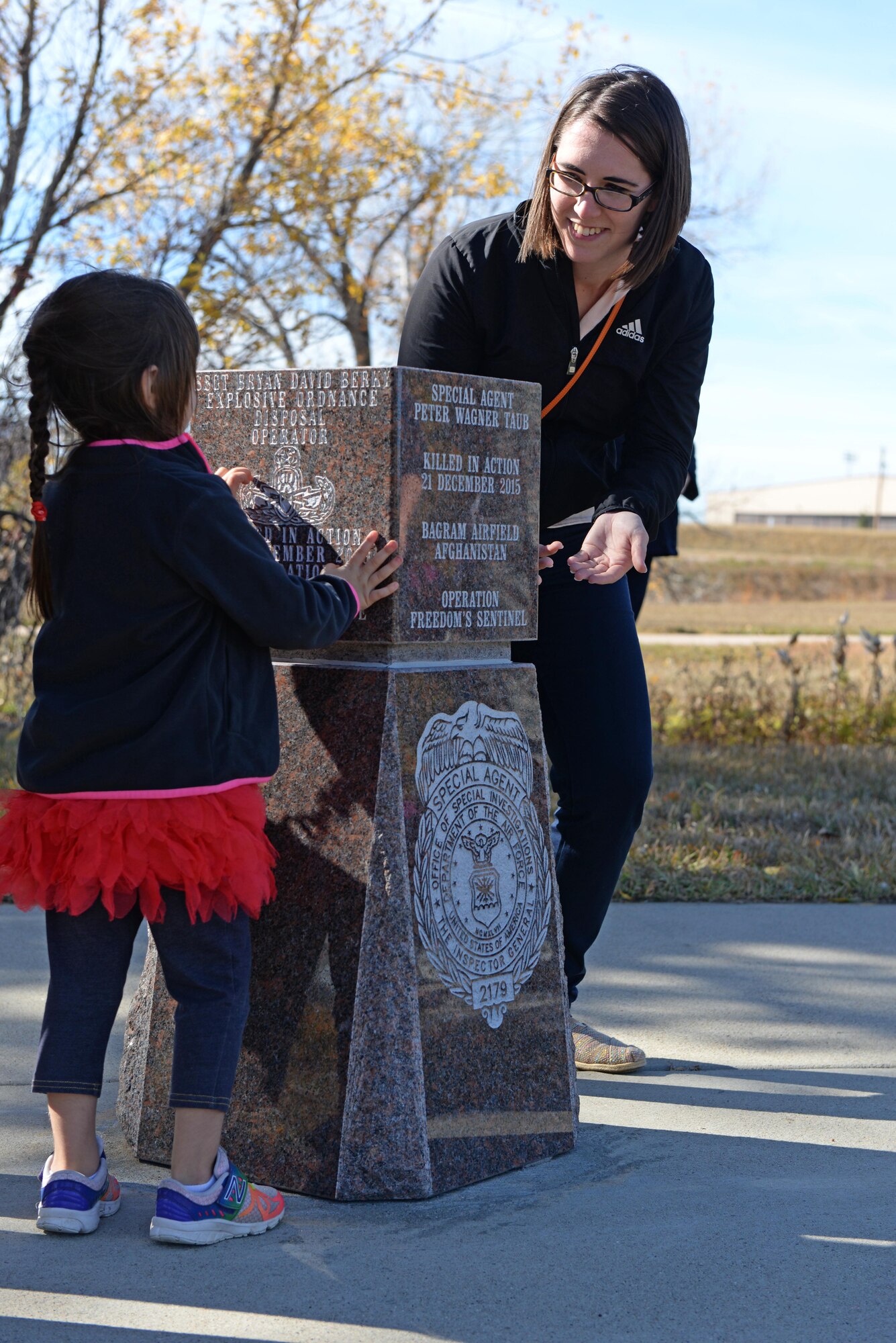 Penelope and Christina Taub, daughter and wife of the late Special Agent Peter Taub, Air Force Office of Special Investigations agent, look at a memorial during an unveiling ceremony at Ellsworth Air Force Base, S.D., Oct. 21, 2016. The memorial was donated by the Rapid City Chamber of Commerce to honor the memory of Taub, who was killed in action near Bagram Airfield, Afghanistan, Dec. 21, 2015. (U.S. Air Force photo by Senior Airman Rebecca Imwalle) 