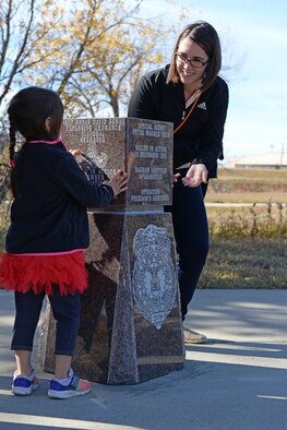 Penelope and Christina Taub, daughter and wife of the late Special Agent Peter Taub, Air Force Office of Special Investigations agent, look at a memorial during an unveiling ceremony at Ellsworth Air Force Base, S.D., Oct. 21, 2016. The memorial was donated by the Rapid City Chamber of Commerce to honor the memory of Taub, who was killed in action near Bagram Airfield, Afghanistan, Dec. 21, 2015. (U.S. Air Force photo by Senior Airman Rebecca Imwalle) 
