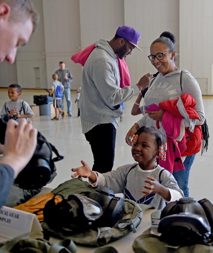 U.S. Air Force Staff Sgt. Ashley Cotton, 7th Logistics Readiness Squadron, smiles as she watches her daughter Laylah learn how to put on a gas mask during Operation Dyess Kids 2016 at Dyess Air Force Base, Texas, Oct. 22, 2016. After going through the deployment processing line and receiving a pre-deployment brief, the children saw numerous displays and demonstrations and were able to, try on gas masks, eat meals ready to eat commonly known as MREs, have their faces painted and much more. (U.S. Air Force photo by Staff Sgt. Kia Atkins)