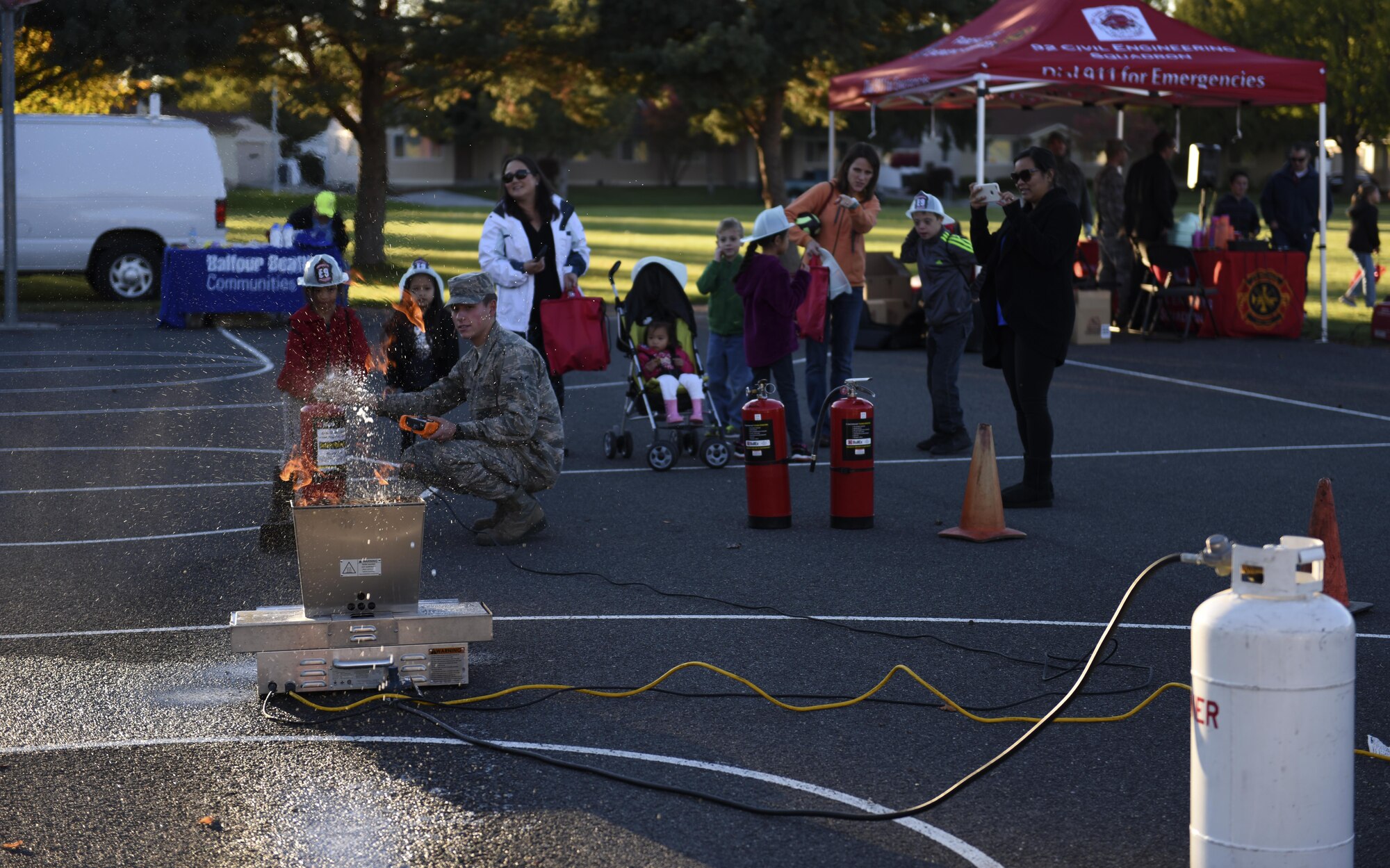A 92nd Civil Engineer Squadron firefighter holds live, fire extinguisher training as part of the Fire Prevention Week Carnival Oct. 12, 2016, at Fairchild Air Force Base. The 92nd CES Fire Department staff used the event to teach children fire safety habits, from crawling through a simulated fire to getting hands-on training using a fire extinguisher and hose. (U.S. Air Force photo/Airman 1st Class Sean Campbell)