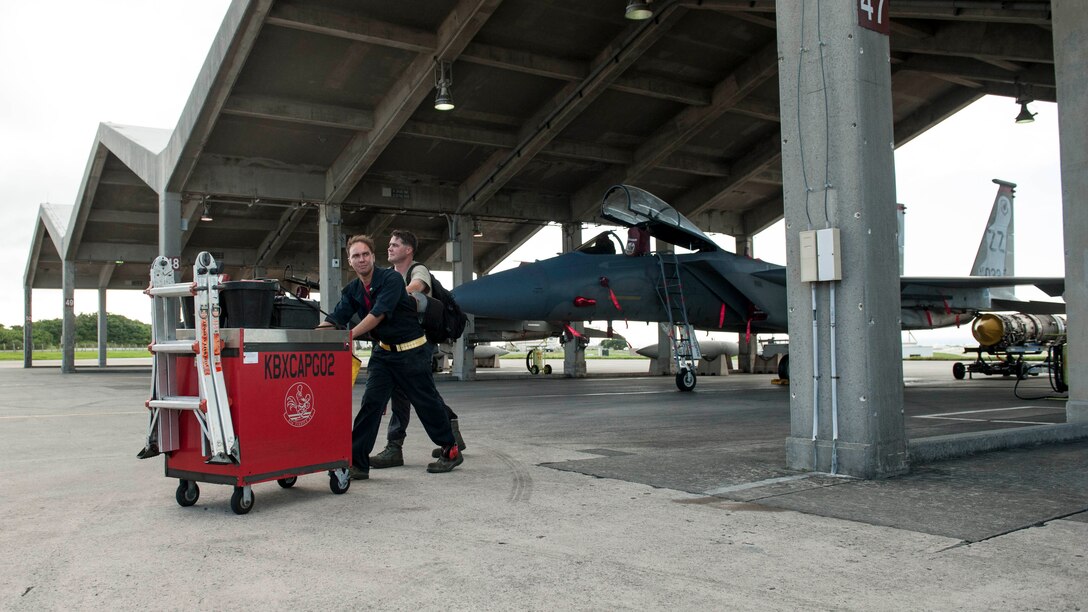 U.S. Air Force Staff Sgt. Carl Petmecky and Senior Airman Alexander Reyes, 67th Aircraft Maintenance Unit crew chiefs, push their tool cart off the flightline during a shift change Oct. 21, 2016, at Kadena Air Base, Japan. Petmecky and Reyes performed maintenance on an F-15 Eagle, an operation that utilizes 24-hour manning to ensure constant mission readiness should the call of duty arise to defend Okinawa and other U.S. interests in the Indo-Asia Pacific region. (U.S. Air Force photo by Senior Airman Peter Reft/Released)