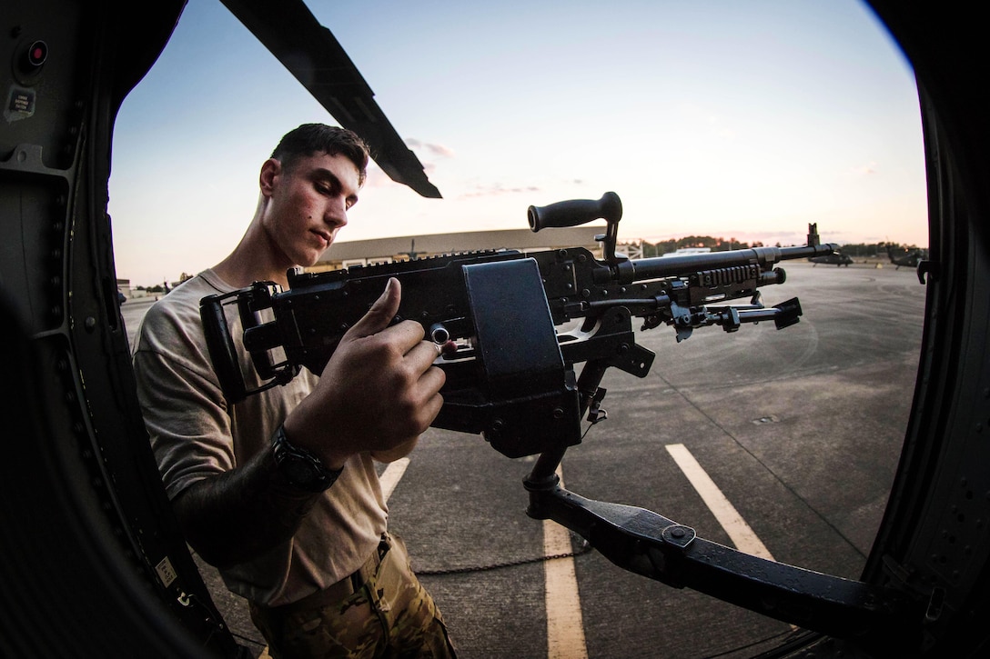 Army Spc. Alexander Haase secures an M240 machine gun on a UH-60 Black Hawk helicopter before participating in a simulated air assault at Fort Bragg, N.C., Oct. 19, 2016. Haase is a crew chief assigned to the 2nd Battalion, 82nd Combat Aviation Brigade. Army photo by Capt. Adan Cazare