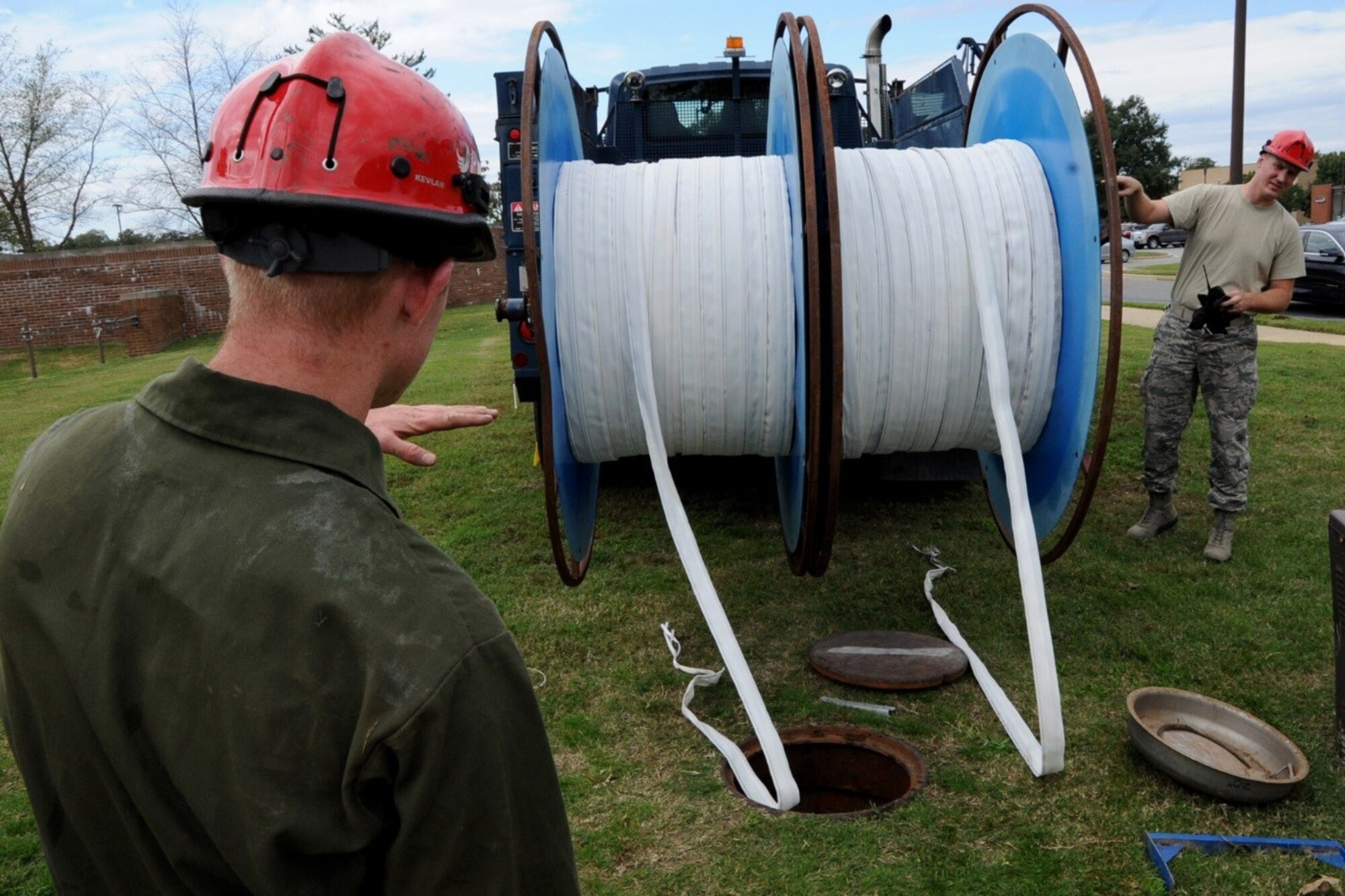 Senior Airman Cameron Porter and Airman First Class Michael Eckhoff, 744th Communications Squadron cable antenna maintenance, lower inner duct fabric for running 1,600 feet of fiber optic cable to the flight line on Joint Base Andrews Oct. 13, 2016. The 744th CS delivers many cyberspace operations such as secure networks, voice communications services, and communications infrastructure and intrusion detection systems within the National Capital Region.  (U.S Air Force photo/Tech. Sgt. Matt Davis)