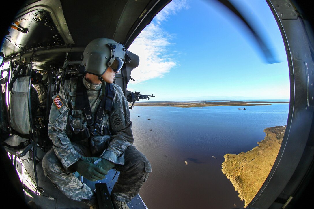 An Army crew chief checks for clearance while a soldier fires an M240 machine gun at targets from a UH-60 Black Hawk helicopter during an aerial gunnery training exercise near Marine Corps Outlying Field Atlantic, N.C., Oct. 22, 2016. Army photo by Sgt. Steven Galimore 